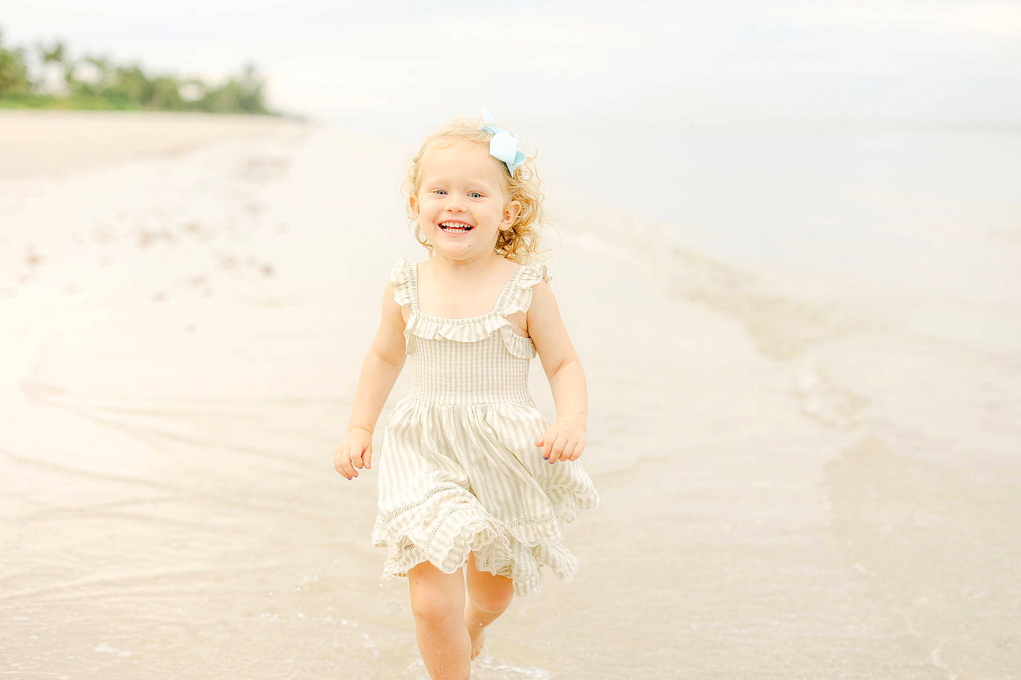 Olivia is registered to the contest to win money with this photo: baby_toddler_clothing, beach, blond, body_of_water, child, day_dress, dress, flash_photography, fun, happy, joy, landscape, people_in_nature, people_on_beach, person, sand, skin, sky, sleeve, smile