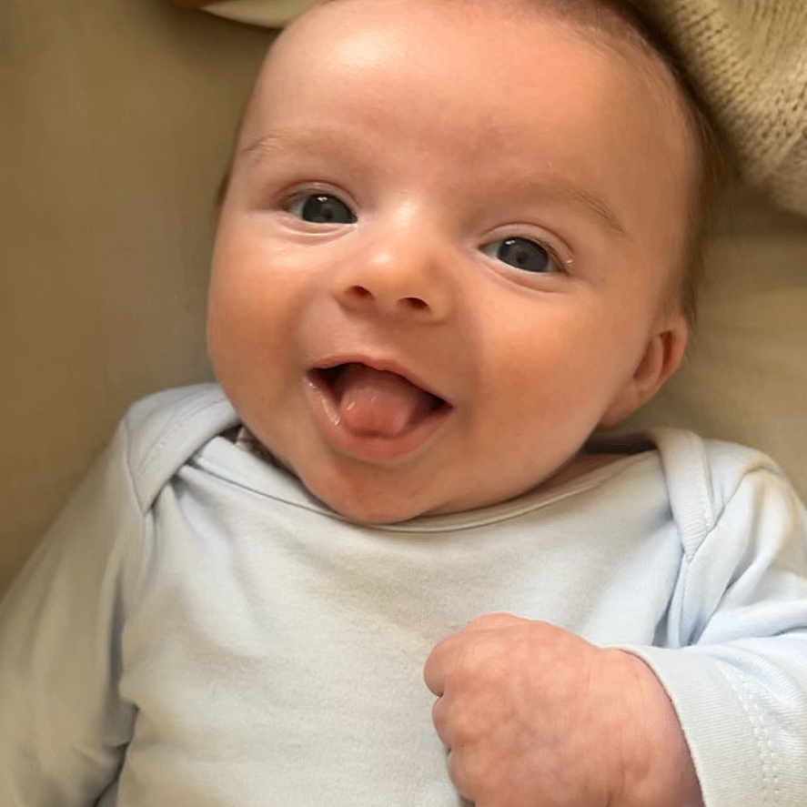 Rudi-Greyson joined the competition — help win amazing prizes! baby, cheeky, child, closeup, clothing, cozy, cute, face, hand, happy, indoors, infant, knitted_blanket, lying_down, playful, portrait, smiling, soft_toys, tongue_out, young