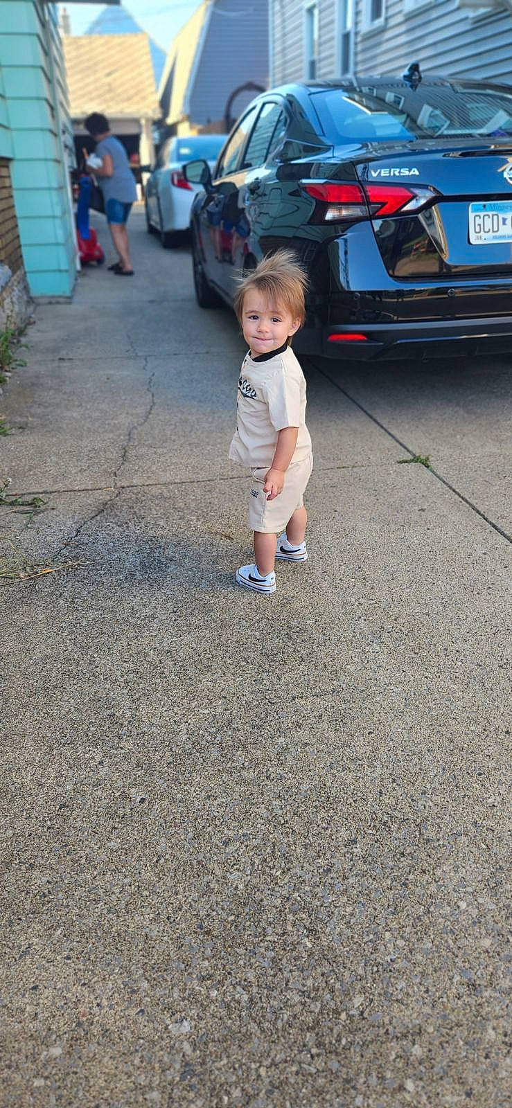 Nicholas is registered to the contest to win money with this photo: asphalt, automotive_design, automotive_exterior, automotive_lighting, automotive_tire, bumper, car, joy, motor_vehicle, parking, person, personal_luxury_car, road, road_surface, shorts, sidewalk, tire, toddler, trunk, vehicle