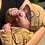 baby, infant, child, person, arm, hand, clothing, hat, patterned, yellow, sucking_thumb, curious, indoor, stack, video_games, black_shirt, skin, closeup, portrait, holding