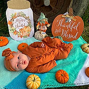 Oaklynn is registered to the contest to win money with this photo: art, baby, baby_toddler_clothing, calabaza, child, comfort, cucurbita, gourd, grass, green, leaf, natural_foods, orange, plant, pumpkin, stuffed_toy, textile, toddler, vegetable, winter_squash