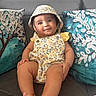 Nahara Rosario is registered to the contest to win money with this photo: baby, child, comfortable, couch, cute, decorative_pillows, face, feet, floral_pattern, hands, hat, home, indoor, infant, pillows, portrait, romper, seated, smile, young_child