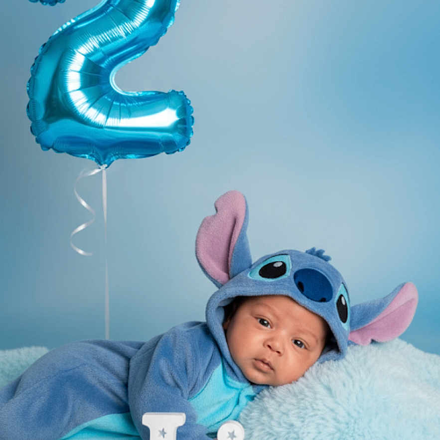 Liam joined the competition — help win amazing prizes! baby, background, balloon, birthday, blue, celebration, child, costume, cute, decor, fluffy_blanket, indoors, letters, lying_down, name, number_two, portrait, soft_toys, stitch, studio