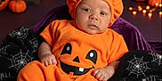 Liam joined the competition — help win amazing prizes! baby, pumpkin_costume, halloween, orange, purple, blanket, spiderweb, black, decorations, ghost, bat, pumpkin, candle, cute, indoors, portrait, child, holiday, festive, smiling