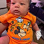 baby, infant, orange_clothing, mickey_mouse, donald_duck, goofy, pluto, onesie, mitten, person, indoor, furniture, storage_bins, dresser, carpet, cute, portrait, child, cartoon_characters, cute_baby