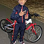 child, boy, bicycle, bike, tracksuit, sneakers, outdoor, night, tree, pavement, gesture, posing, flash, sportswear, casual, person, young, standing, expression, park