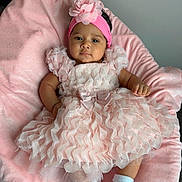 Mia joined the competition — help win amazing prizes! baby, infant, pink_dress, headband, flower, blanket, soft_texture, cute, child, footwear, socks, indoor, portrait, smiling, lying_down, comfortable, decorative, clothing, person, toddler