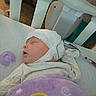baby, sleeping, crib, blanket, pacifier, medical_wires, cap, infant, bed, resting, child, peaceful, indoors, person, healthcare, soft, cozy, cute, newborn, quiet