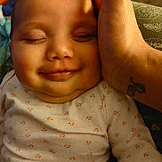Kingsley is registered to the contest to win money with this photo: apparel, baby, child, closeup, clothing, comfort, cute, expression, face, hand, infant, newborn, person, portrait, resting, skin, sleeping, smile, tattoo, warm_light