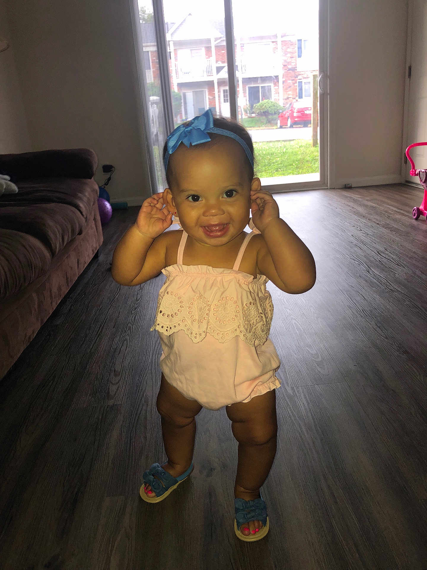 Syrenity joined the competition — help win amazing prizes! toddler, child, smiling, indoor, living_room, flooring, headband, blue_bow, pink_outfit, shoes, happy, person, baby, standing, playful, sunlight, door, furniture, couch, home