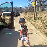 Michael joined the competition — help win amazing prizes! child, sidewalk, car, open_car_door, sunglasses, bucket_hat, shorts, tshirt, shoes, shadow, tree, parking, street, sunny, outdoor, casual_clothing, pose, smile, road_sign, hand_tattoo