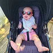 Hannah joined the competition — help win amazing prizes! baby, sunglasses, stroller, infant, tongue_out, heart_shaped_glasses, pink_shorts, bib, sunlight, outdoor, wooden_deck, baby_boy, baby_girl, seat_belt, happy, cute, child, summer, smiling, fun