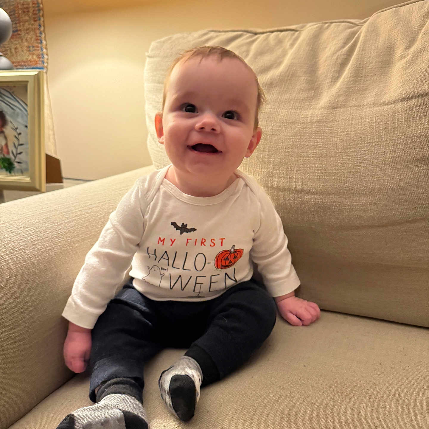 Cooper joined the competition — help win amazing prizes! baby, celebration, child, couch, cozy, cute, decor, halloween, happy, home, indoors, infant, lamp, person, portrait, seated, shirt, smiling, socks, young