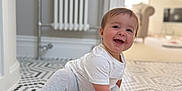 Ivy joined the competition — help win amazing prizes! baby, child, crawling, smiling, floor, tile, hexagonal_tile, white_clothing, gray_clothing, sock, indoor, radiator, furniture, living_room, happy, person, cute, head, hand, home