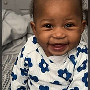 Daniya is registered to the contest to win money with this photo: baby, child, smiling, white_bow, blue_flowers, outfit, bedspread, indoor, happy, cute, person, portrait, sitting, infant, clothing, pattern, headwear, young_child, joyful, room