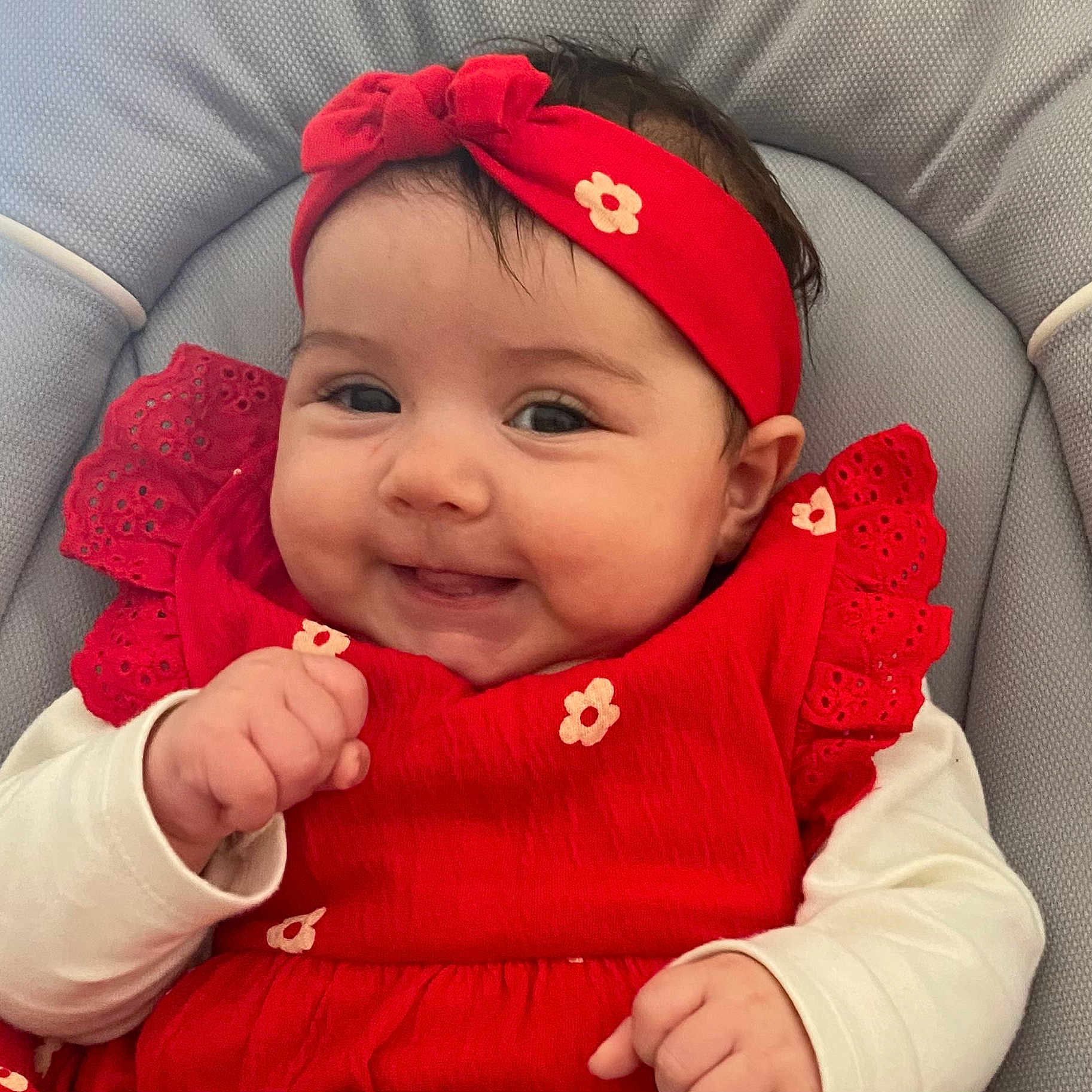 Romy participe au concours pour gagner de l'argent avec cette photo : baby, baby_clothing, child, closeup, comfortable, cute, expression, face, hands, happy, headwear, indoors, infant, padded_chair, portrait, red_dress, red_headband, smiling, white_sleeves, young