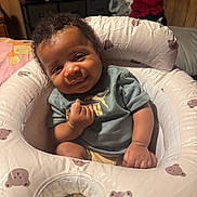Drayce joined the competition — help win amazing prizes! baby, infant, child, smiling, portrait, indoor, bedroom, cushion, lounger, bear_pattern, puma_shirt, curly_hair, seated, happy, face, hands, legs, furniture, blanket, home