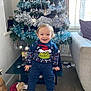 Luca joined the competition — help win amazing prizes! toddler, child, smiling, christmas_tree, holiday, grinch_sweater, tinsel, ornaments, teddy_bear, santa_hat, indoor, carpet, sofa, window, curtains, table, festive, happy, cute, portrait