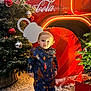 toddler, child, winter_clothing, snowsuit, snow, christmas_tree, ornaments, red_truck, coca_cola, holiday_lights, festive, outdoor, smiling, person, footwear, celebration, decoration, seasonal, cute, happy