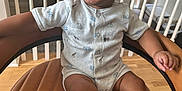 Jaxon is registered to the contest to win money with this photo: child, toddler, smiling, chair, leather, hand, baby_clothes, indoor, wood_floor, railing, window, natural_light, happy, person, cute, sitting, curly_hair, infant, home, portrait