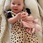 Ella a rejoint le concours — aidez-le/la à gagner de superbes lots ! baby, baby_girl, basket, child, clothing, comfort, cushion, cute, face, hair_bows, hand, happy, indoors, infant, leopard_print, person, plush_toy, sleeping_basket, smiling, soft_toy