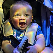 Emmanuel is registered to the contest to win money with this photo: baby, infant, child, car_seat, stroller, seat_belt, smile, laughing, rainbow_light, colorful, holding_shoe, shoe, chubby_arms, onesie, clothing, closeup, portrait, soft_lighting, fabric, buckle