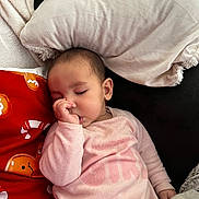 Adélina a rejoint le concours — aidez-le/la à gagner de superbes lots ! baby, child, sleeping, thumb_sucking, pillow, blanket, couch, red_pillow, pink_clothing, onesie, closed_eyes, hand, ear, hair, peaceful, indoor, nap, soft_texture, plush, comfort