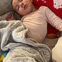 Adélina a rejoint le concours — aidez-le/la à gagner de superbes lots ! child, baby, infant, sleeping, blanket, pillow, couch, red_pillow, candy_pattern, cozy, soft_texture, nap, peaceful, indoors, onesie, plush, comfort, resting, face, hand
