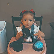 Promise joined the competition — help win amazing prizes! child, toddler, girl, portrait, sitting, high_chair, indoors, home, table, toy, glowing_ball, black_disc, red_bows, overalls, white_shirt, smiling, face, hair, chair, playtime
