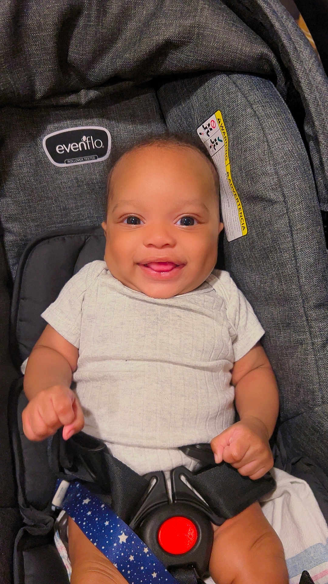 Kauron is registered to the contest to win money with this photo: baby, infant, smile, smiling, car_seat, evenflo, onesie, seat_belt, safety_harness, buckle, close_up, portrait, happy, baby_hands, big_eyes, fabric, warning_label, stroller, cute, tan_skin