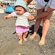 Elena participe au concours pour gagner de l'argent avec cette photo : baby, child, adult, beach, sand, pebbles, sunhat, pink_shorts, white_shirt, sunglasses, pacifier, supporting_hand, barefoot, summer, sunny, outdoor, buildings, people, walking, playing