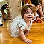 adult, background, blue_eyes, casual_clothing, child, crawling, curly_hair, family, floor, happy, home, indoor, lace, people, person, pink_bow, smiling, toddler, white_dress, wooden_floor