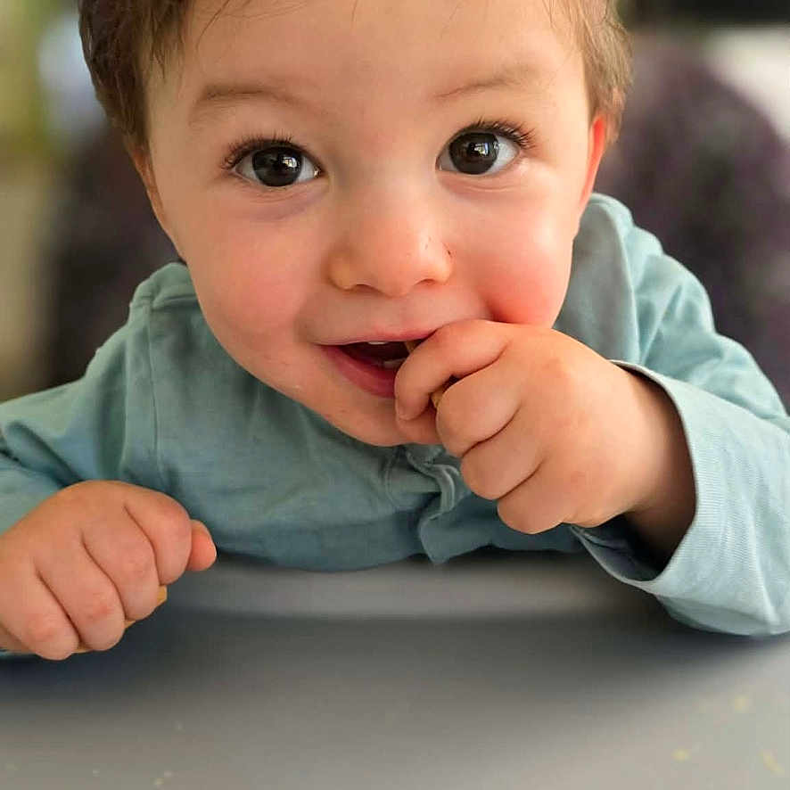 Maël a rejoint le concours — aidez-le/la à gagner de superbes lots ! child, toddler, face, hands, curious, cute, portrait, indoor, clothing, blue_shirt, expression, person, young_child, closeup, baby, smiling, skin, hair, eyes, table