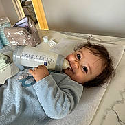 Pablo a rejoint le concours — aidez-le/la à gagner de superbes lots ! baby, bottle, milk, smiling, towel, marble_countertop, indoor, baby_clothing, happy, child, face, hand, hair, feeding, baby_care, room, container, table, soft_texture, infant