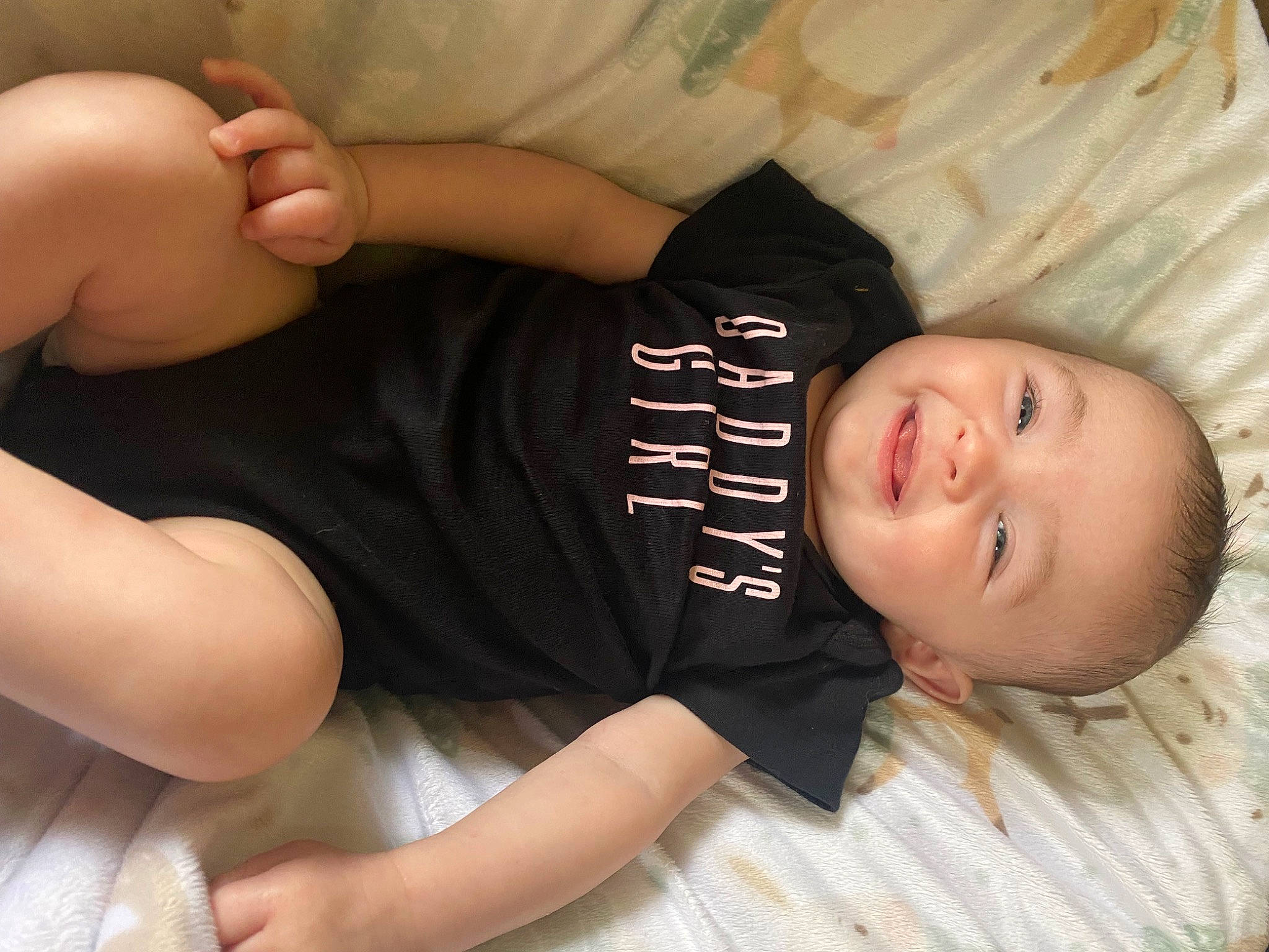 Aubree is registered to the contest to win money with this photo: arm, baby_toddler_clothing, black_hair, comfort, elbow, finger, flooring, gesture, hand, head, human_body, joy, knee, leg, person, skin, sleeve, smile, stomach, thigh