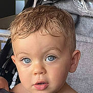 édouard a rejoint le concours — aidez-le/la à gagner de superbes lots ! toddler, child, blue_eyes, wet_hair, curious_expression, stroller, gray_fabric, cup, close_up, face, portrait, indoor, young_child, person, baby, eyelashes, skin, head, cute, innocent