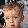 toddler, child, blue_eyes, wet_hair, curious_expression, stroller, gray_fabric, cup, close_up, face, portrait, indoor, young_child, person, baby, eyelashes, skin, head, cute, innocent