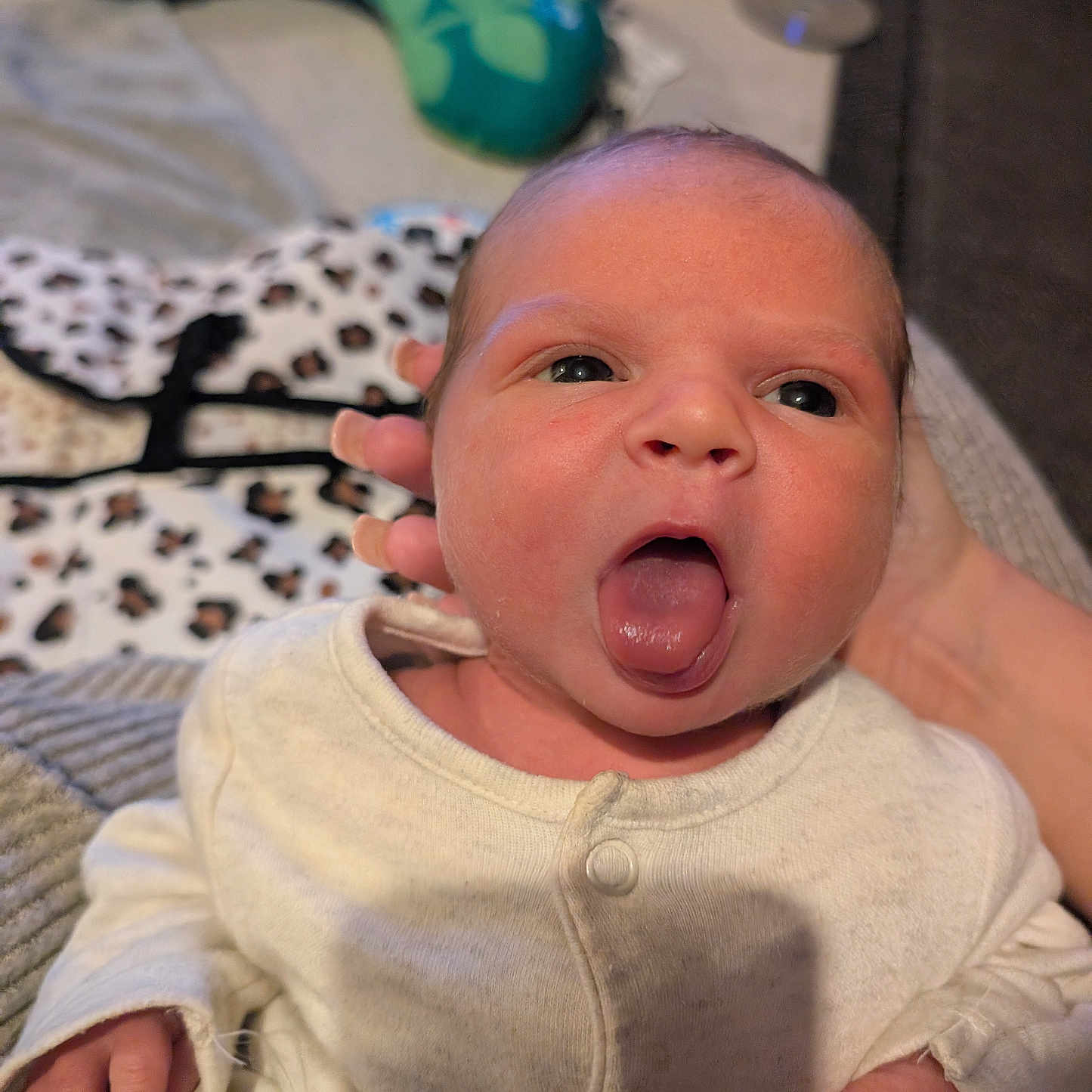 Zeniyah is registered to the contest to win money with this photo: baby, baby_pillow, blurred_background, child, cozy, cute, expression, face, hand, human, indoor, infant, newborn, onesie, person, portrait, skin, soft_toys, support, tongue_out