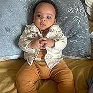 Jeremiah is registered to the contest to win money with this photo: baby, child, infant, pillow, clothing, jacket, pants, socks, bed, blanket, hands, face, eyes, hair, indoor, person, portrait, seated, cute, expression