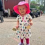 Adalynn is registered to the contest to win money with this photo: cartoon_pattern, chalk_drawings, child, colorful_dress, daytime, leggings, outdoor, pavement, people_in_background, person, pink_hat, playful, purple_shoes, red_building, smiling, strollers, sunny_day, toddler, trees, wooden_crafts