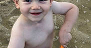 Levi is registered to the contest to win money with this photo: toddler, child, smiling, wet_hair, sand, shovel, bucket, water, play, outdoor, bare_chested, summer, happy, fun, person, closeup, cute, recreation, daylight, skin