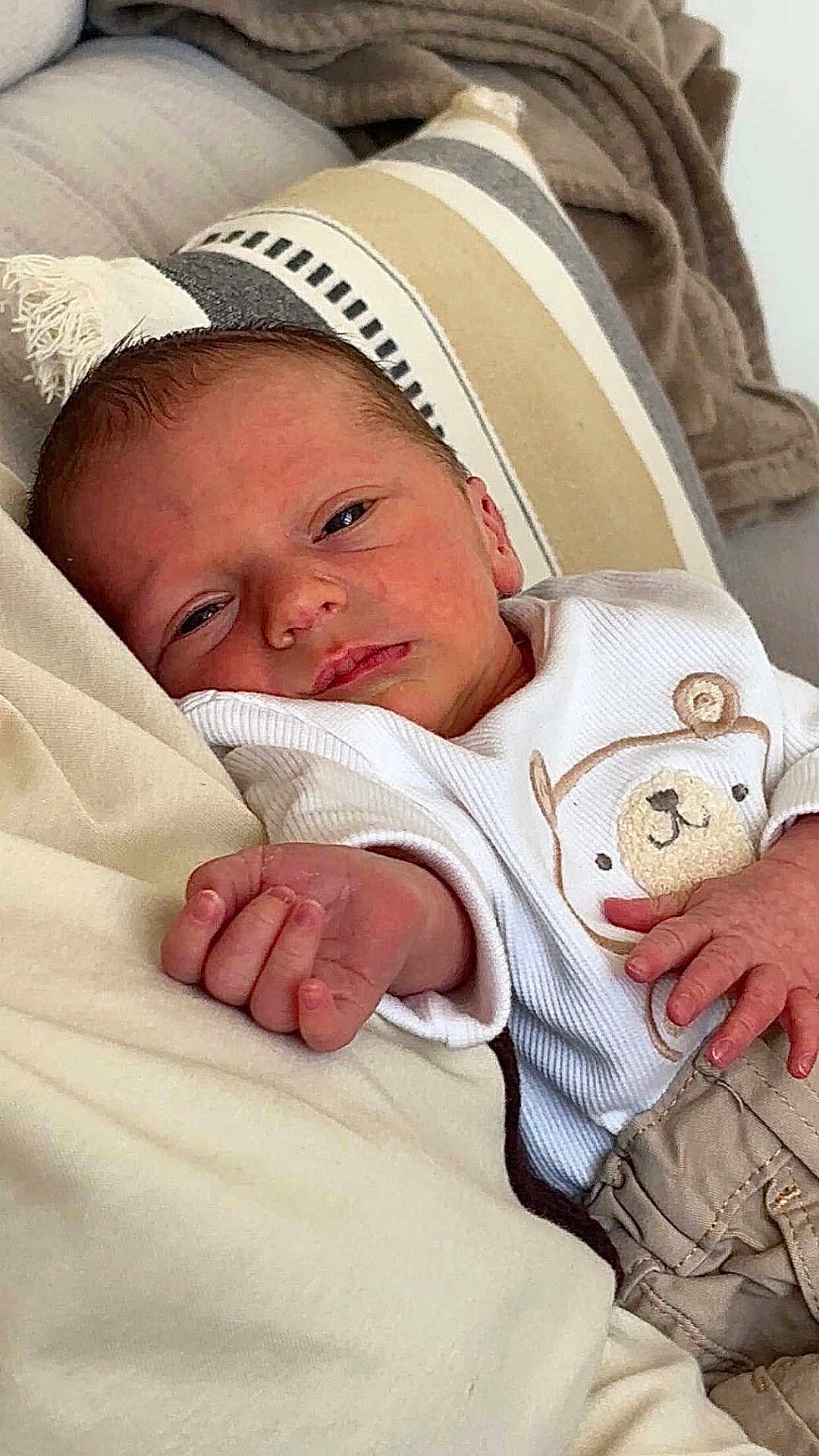 Siméo participe au concours pour gagner de l'argent avec cette photo : newborn, baby, infant, face, hand, couch, cushion, blanket, clothing, teddy_bear, portrait, indoors, child, relaxing, cute, soft, warm_colors, sleepy, resting, young