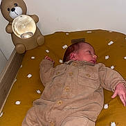 Siméo a rejoint le concours — aidez-le/la à gagner de superbes lots ! baby, infant, clothing, onesie, sock, bed, cushion, lamp, bear_lamp, nursery, sleeping, child, soft_toys, yellow_cushion, wooden_bed, indoors, cute, resting, newborn, room