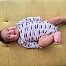 baby, child, couch, cozy, cute, face, furniture, happy, head, indoors, infant, lying_down, onesie, plush, portrait, red_cars, skin, small_person, smile, yellow_couch
