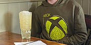 Jake is registered to the contest to win money with this photo: boy, casual, chair, child, crushed_ice, fork, framed_picture, glass, happy, hoodie, indoor, knife, napkin, portrait, red_hair, smiling, table, wall, wooden_table, xbox