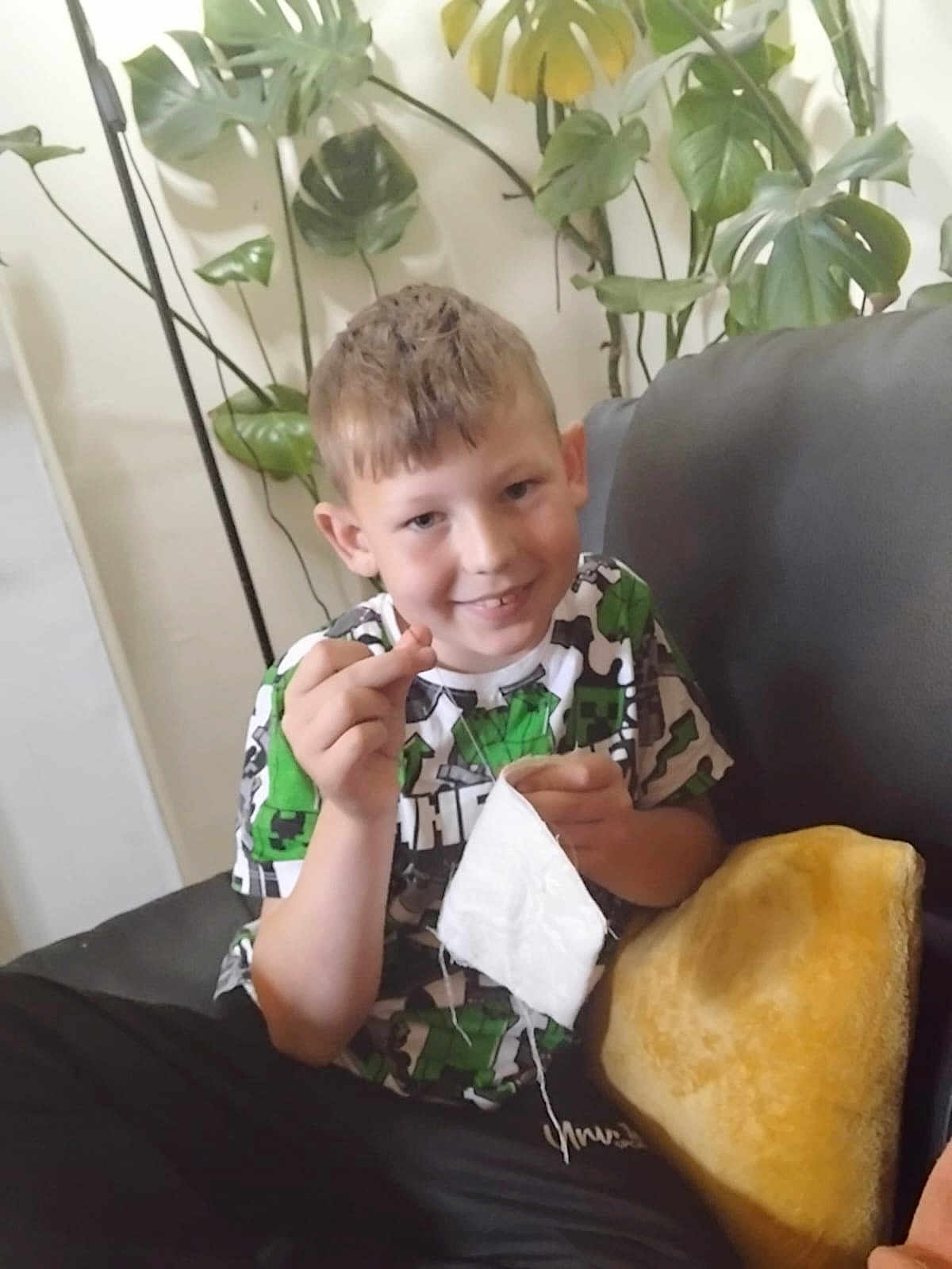Brayden joined the competition — help win amazing prizes! boy, casual_clothing, child, couch, cozy, fabric, greenery, hand, happy, home, indoor, living_room, pillow, plant, portrait, relaxed, seated, short_hair, smiling, young