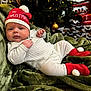 baby, infant, christmas_hat, holiday, christmas_tree, ornament, wrapped_presents, gift_wrapping, green_blanket, onesie, red_booties, cozy, festive, portrait, face, lying_down, soft_texture, warm_lighting, decoration, cozy_christmas