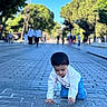 Izna joined the competition — help win amazing prizes! child, toddler, crawling, outdoor, promenade, cobblestones, trees, park, sunlight, blue_sky, white_shirt, blue_pants, dark_hair, portrait, street, pavement, people, background, travel, daylight
