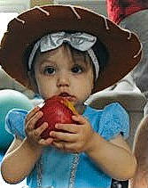 Elle is registered to the contest to win money with this photo: baby, child, eating, finger, food, fruit, fun, happy, headwear, helmet, mouth, natural_foods, nose, person, personal_protective_equipment, produce, sharing, sweetness, tableware, thigh