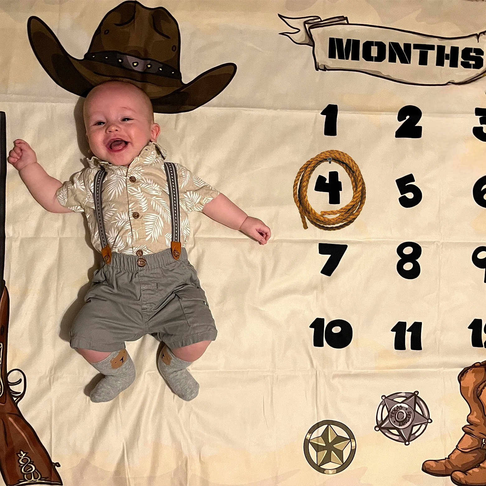 Greyson is registered to the contest to win money with this photo: baby, clothing, cowboyhat, face, firearm, footwear, gun, handgun, hat, head, hosiery, person, photography, portrait, rifle, shoe, shorts, sock, text, weapon